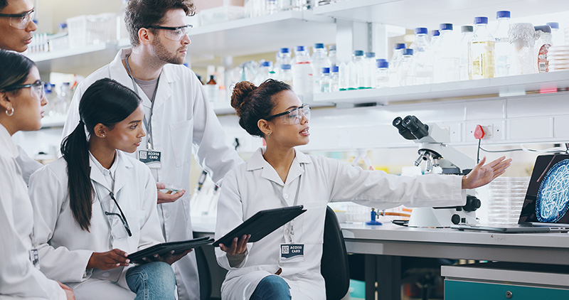 Scientists in a lab viewing an image on a laptop.