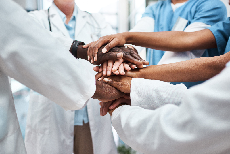 Healthcare professionals standing together with their hands stacked.