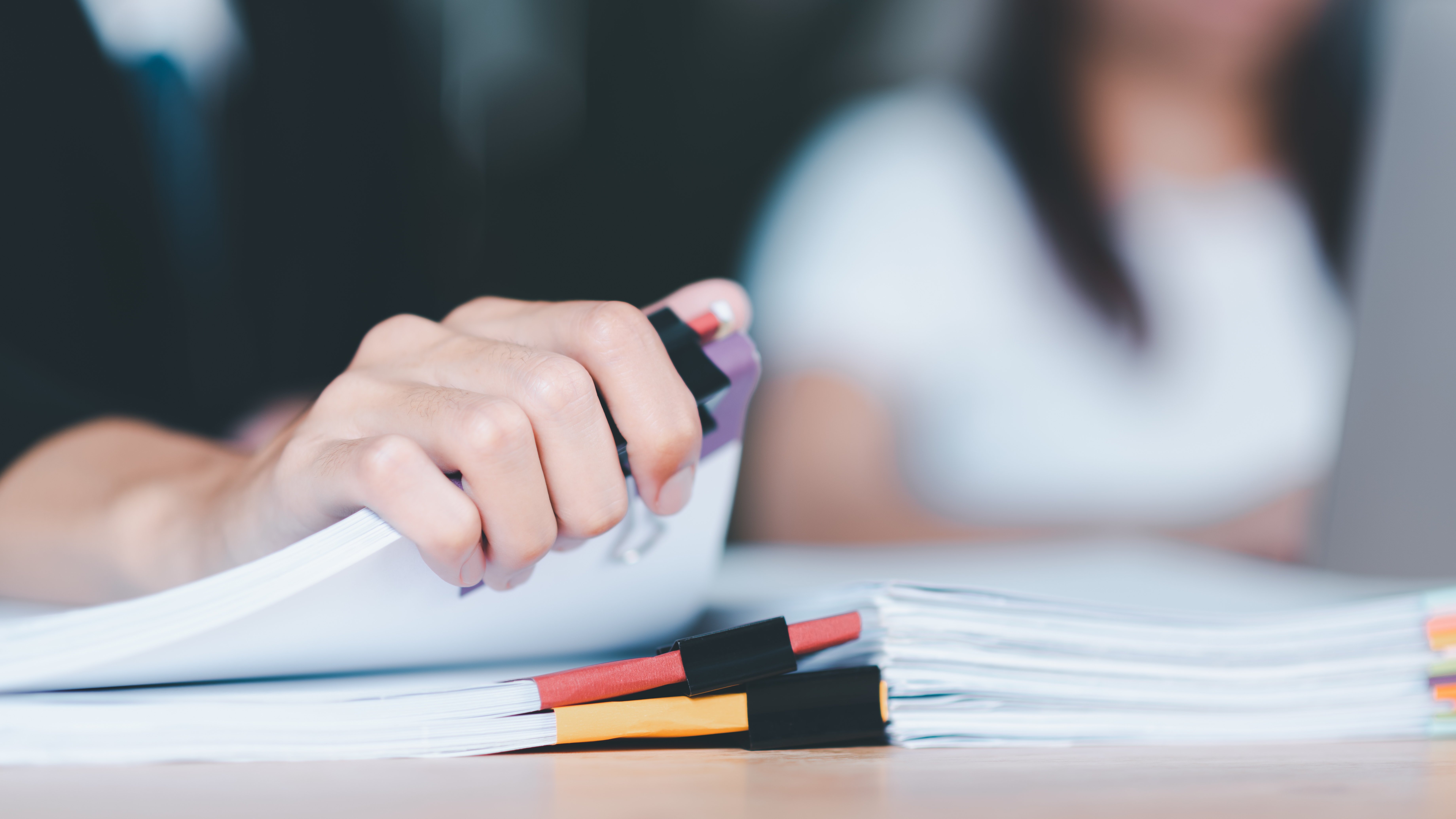 A close-up of a person's hand holding stacks of documents.